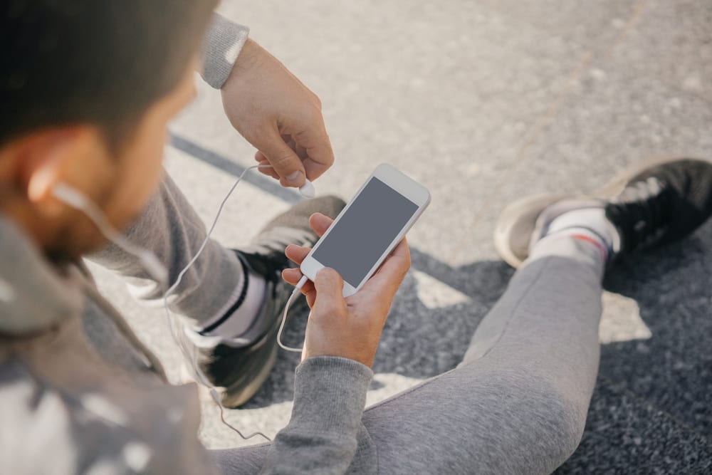 Man,Athlete,Sitting,On,The,Street,With,Mobile,Phone,,Listening